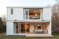 a house made out of shipping containers in the middle of a yard with an open floor plan