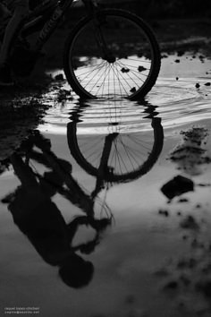 a person riding a bike on top of a body of water next to a puddle