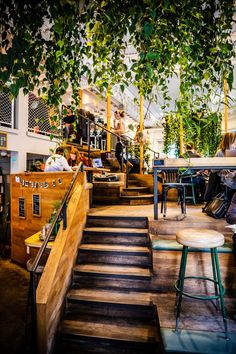 people are sitting at tables and eating in a restaurant with plants growing on the walls