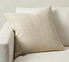 a white couch with a beige pillow on it's back and the bottom part of its arm