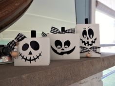 three halloween pumpkins with faces painted on them are sitting on a ledge in front of a window