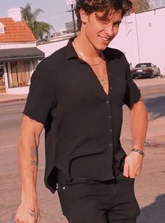 a man walking down the street with his hand in his pocket and wearing a black shirt