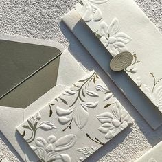 two envelopes with white and gold designs on them