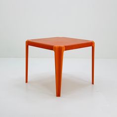 an orange plastic table on a white surface with no one around it or someone else