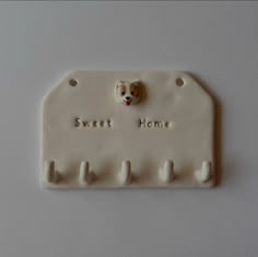 a white ceramic sign with a dog's head on it that says sweet home