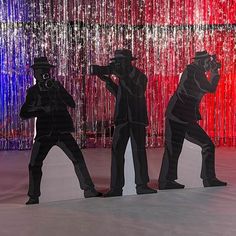 three silhouettes of people in front of a red, white and blue backdrop with streamers