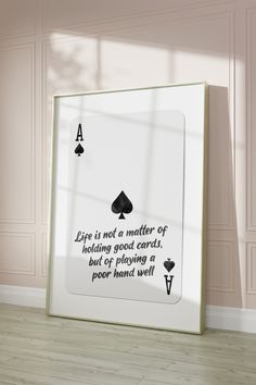 a white frame sitting on top of a hard wood floor next to a wall with a quote about playing cards