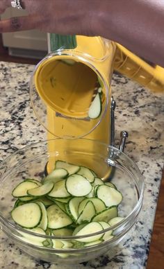 a person pouring juice into a bowl filled with sliced cucumbers