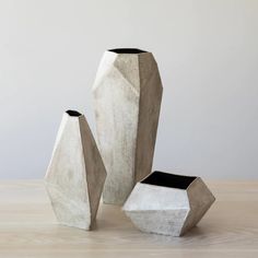 three cement vases sitting on top of a wooden table