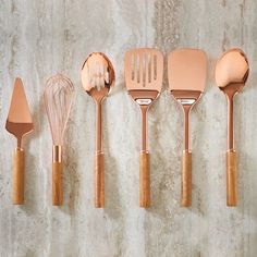 five kitchen utensils lined up against a wall