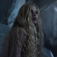 a woman with long blonde hair standing in the dark