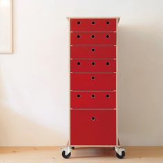 a tall red cabinet sitting on top of a wooden floor next to a white wall