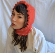 a woman wearing a red knitted hat and scarf on top of a white sheet