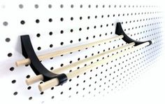 a pair of black and white wall mounted hooks on the side of a pegboard