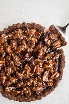 a chocolate tart topped with pecans on top of a table