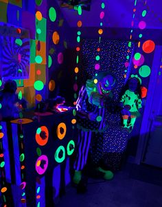 two people standing next to each other in a room with neon lights on the walls