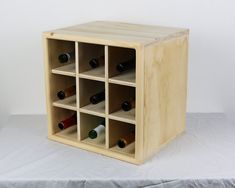 a wooden wine rack filled with bottles on top of a white sheeted tablecloth