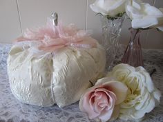 there is a white pumpkin with pink flowers on the table next to two vases