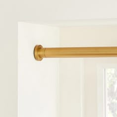 a curtain rod is hanging in front of a window with white walls and windowsills