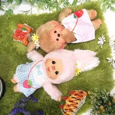 two teddy bears laying next to each other on top of a green carpet covered in flowers