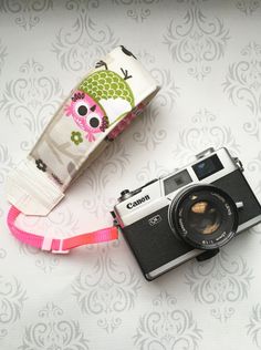 an old camera with a strap attached to it sitting on a table next to a roll of fabric