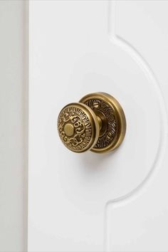 an ornate brass door handle on a white door with gold knobs and decorative details