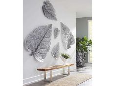 three metal leaf wall hangings mounted on a white wall next to a wooden bench