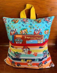 a colorful bag sitting on top of a wooden floor next to a wall with cartoon characters