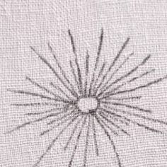 an embroidered piece with needles in it on a white cloth, the image is made up of