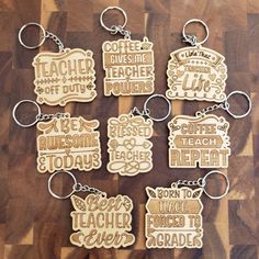 six wooden keychains with words on them sitting on a wood surface, each one has a different type of teacher's name