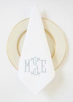 a white napkin with the word ms e on it sitting next to a gold plate