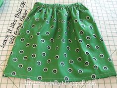 a green skirt with black and white circles on it sitting on a cutting board next to scissors