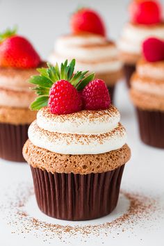 two cupcakes with chocolate frosting and strawberries on top