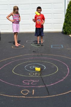 two children standing in front of a driveway with chalk drawings on it