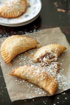 three pastries on a piece of paper with powdered sugar