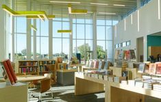 a library filled with lots of books on top of wooden tables next to large windows