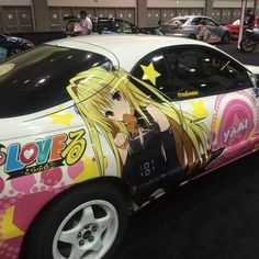 a car that has been painted with anime characters on it's side and is parked in a showroom