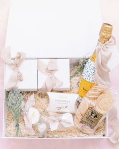 an open gift box containing champagne, cookies and crackers