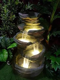 an outdoor fountain with water flowing from it's sides and lights on each side