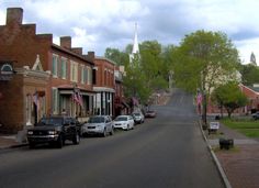 several cars parked on the side of a street in front of brick buildings and trees