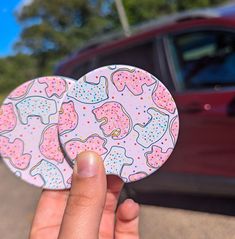 someone holding up a sticker in front of a car that has donuts on it