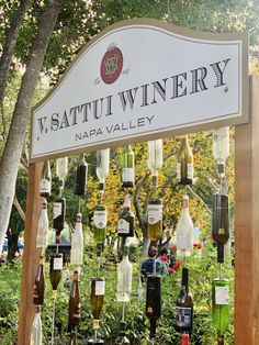 a sign that has some wine bottles on it and is hanging from the side of a tree