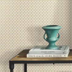 a green vase sitting on top of a wooden table next to a bookshelf