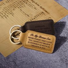 a leather keychain with an engraved message on it sitting next to a pair of scissors