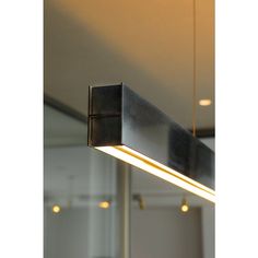 a rectangular light fixture hanging from the ceiling in a room with mirrors and lights around it