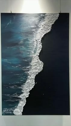 a painting hanging on the wall next to a white framed photo with waves crashing onto it