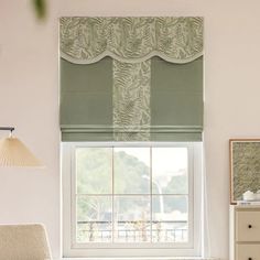 a living room with a couch, chair and window covered in roman shades on the windowsill