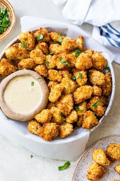 a white bowl filled with tater tots and dipping sauce