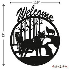 a metal sign that says welcome with two wolfs in the woods and an arrow pointing to