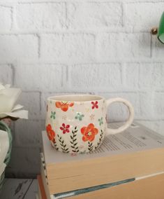 a coffee cup sitting on top of a stack of books next to a green lamp